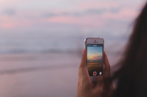 person taking a photo of of open sea and sunset